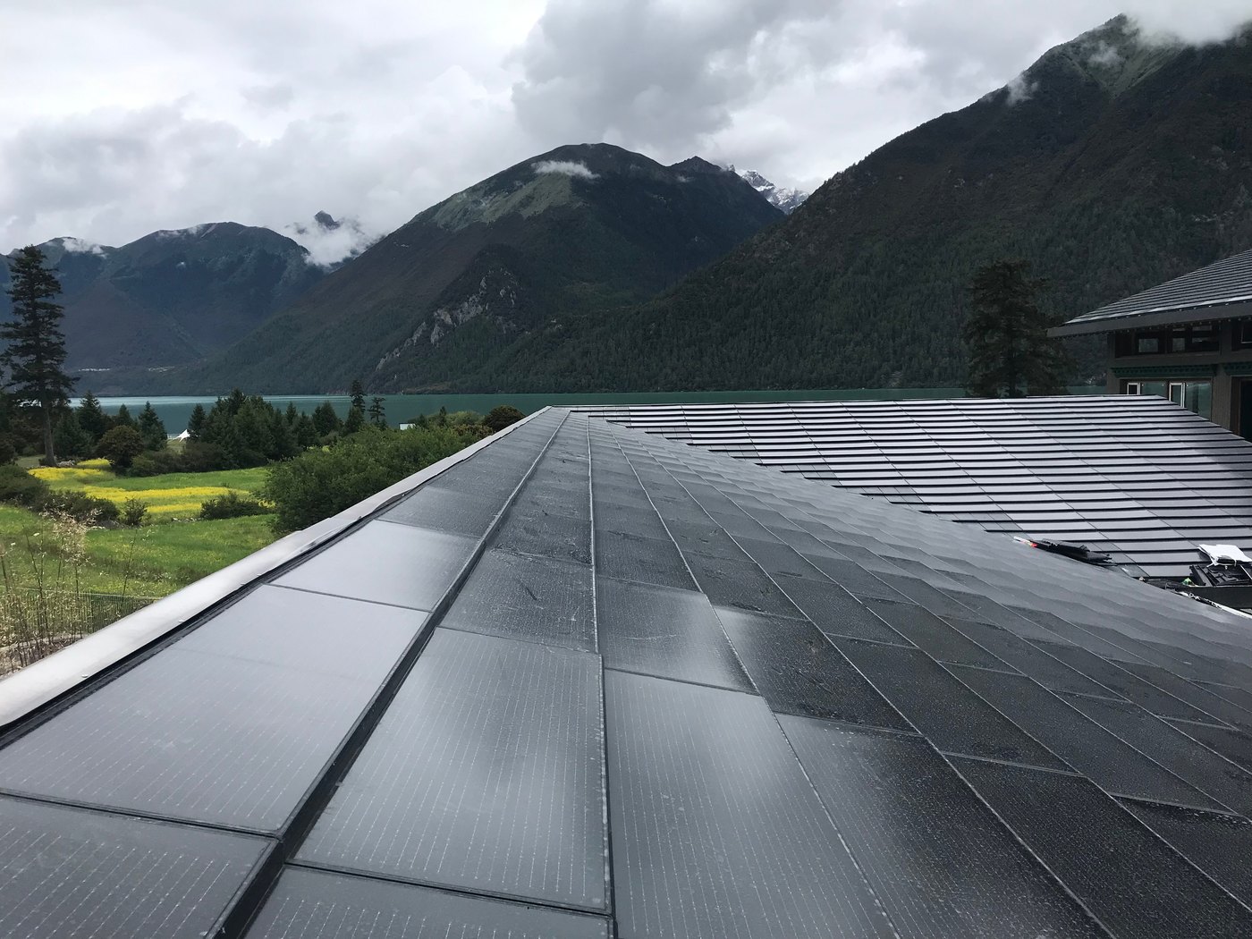 Close view of BIPV solar roof tiles interlocking up to the ridge, cells encapsulated in stone-coated steel